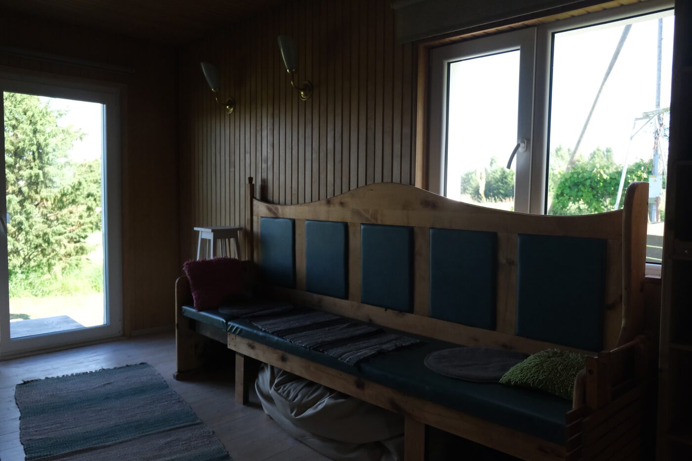 Kulla Saunamaja puiduseintega lounge-tuba ja pink akna all